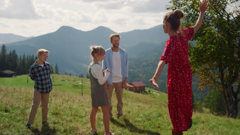 parents playing funny games with children on mountain slope. mother dancing.
