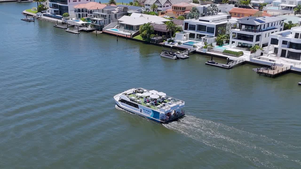 A ferry moves through a residential waterfront, showcasing modern homes and serene water views.
