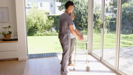 physiotherapist assisting senior woman with walker in bright, sunlit room
