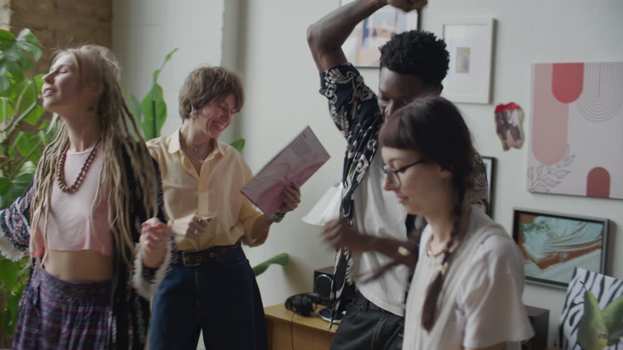 Grupo de jóvenes amigos poniendo discos de vinilo y bailando en una fiesta en casa