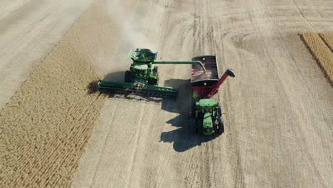 combine tractors harvesting crops on sunny day in saskatchewan, canada