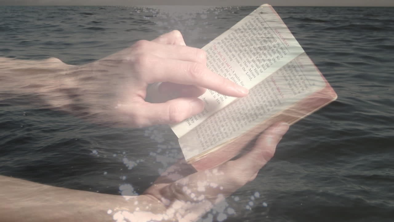 Animation of hands of caucasian man reading bible over seascape