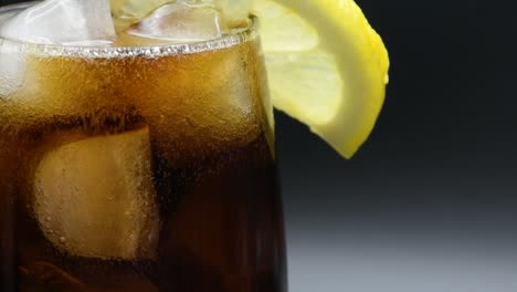 vaso lleno de cola con cubitos de hielo y una rodaja de limón