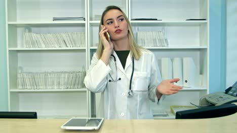 young stressed woman yelling and gesturing while speaking on telephone at hospital reception