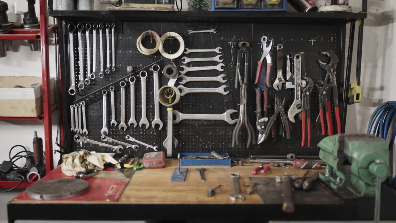 Wide shot of a well-organized mechanic's workshop featuring a tool, wooden workbench, and a vise