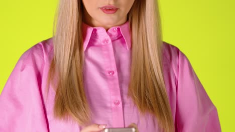 blonde woman scrolling a smartphone touch screen then surprised astonished face expression, colorful studio shot