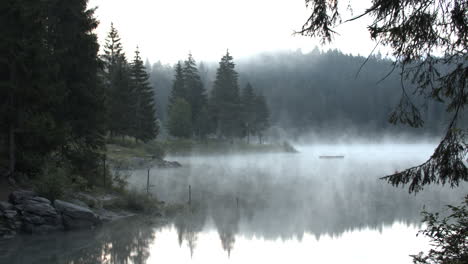 fog rising through a lake and forest on a cold morning - panning shot