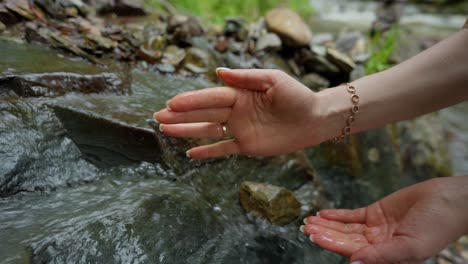 woman's hands cupping water from a mountain stream