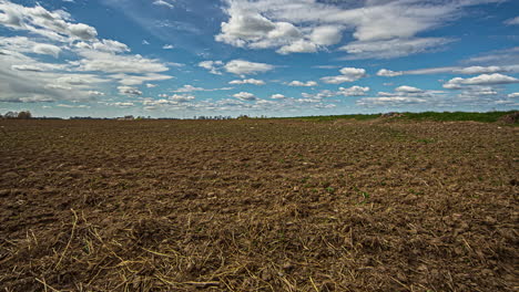 Ackerland-Mit-Wolken,-Die-Sich-Im-Blauen-Himmel-Bewegen