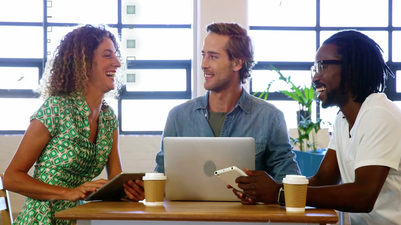 Woman approaching left joining two colleagues at table sharing phone tablet laptop, reviewing files