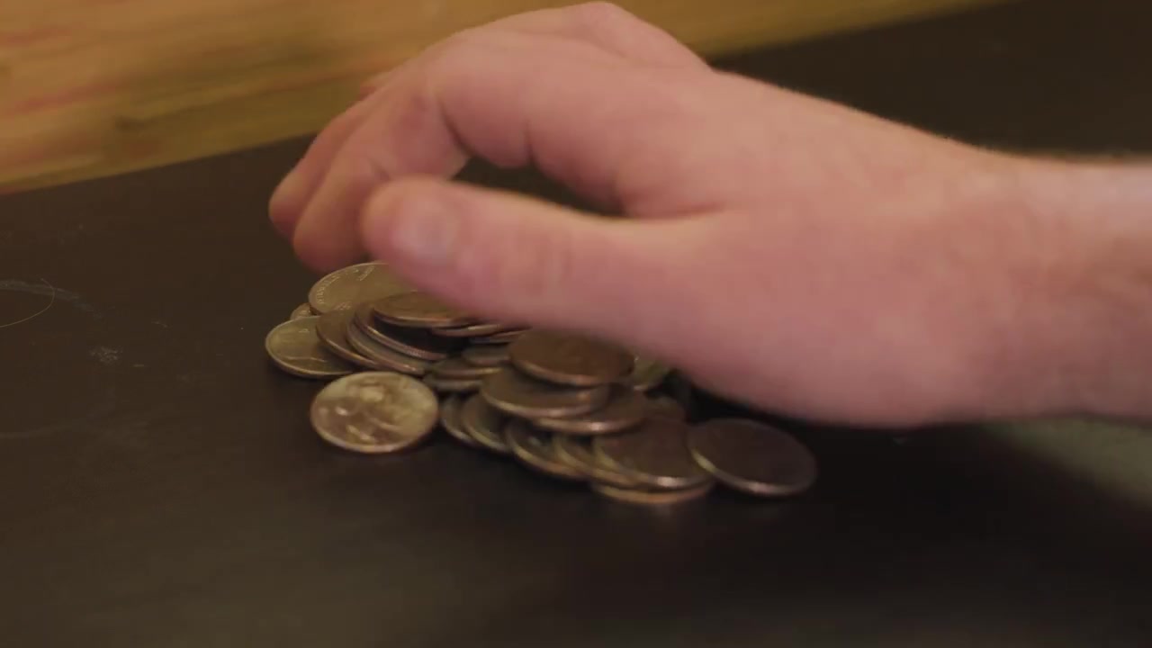 Close-up de moedas USD caindo sobre uma mesa
