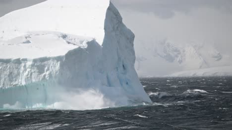 día de tormenta con agua salpicando contra un gran iceberg