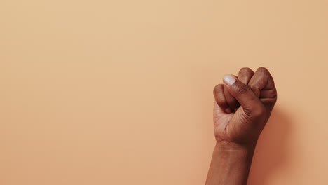 cerca de la mano de un hombre biracial mostrando un signo de paz con espacio de copia en fondo naranja.