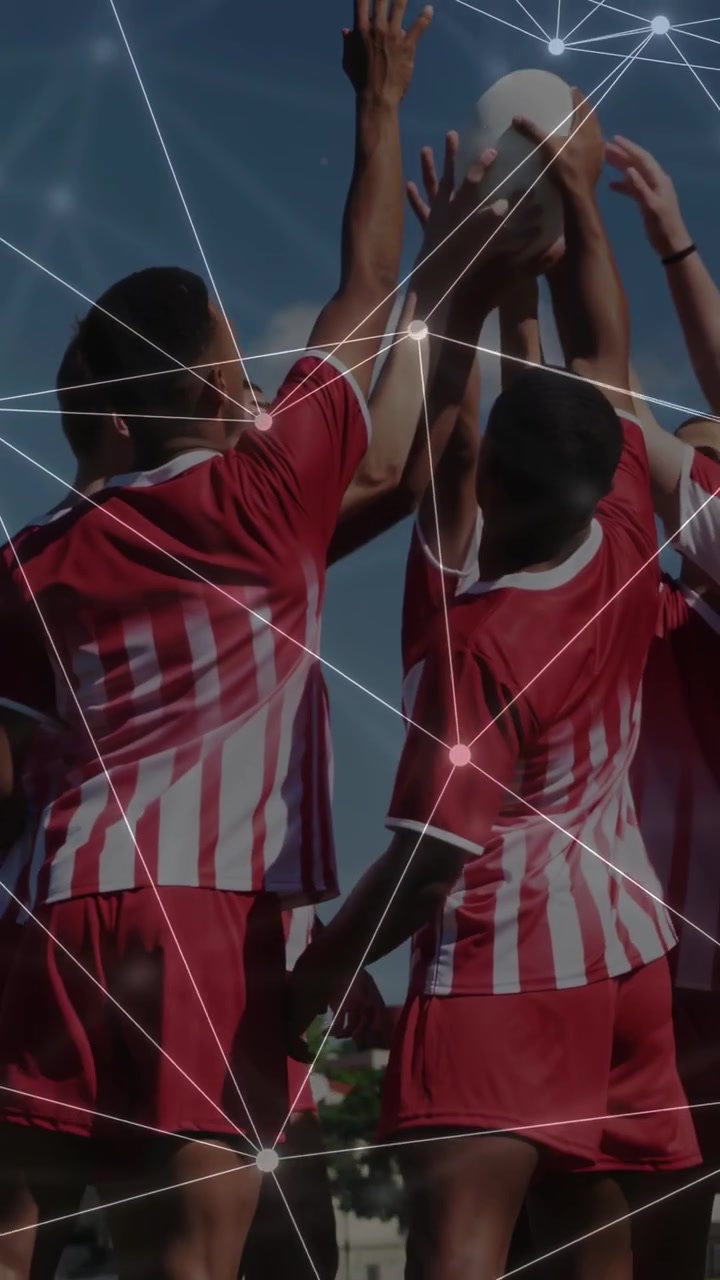 Video verticale: Squadra di calcio che si riunisce in cerchio, unisce le mani e alza una palla bianca, con una rete che evidenzia il rituale.