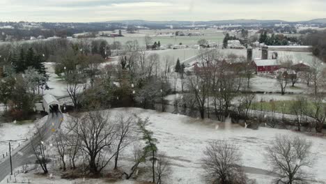 amish horse and buggy enter white covered bridge during winter snowstorm