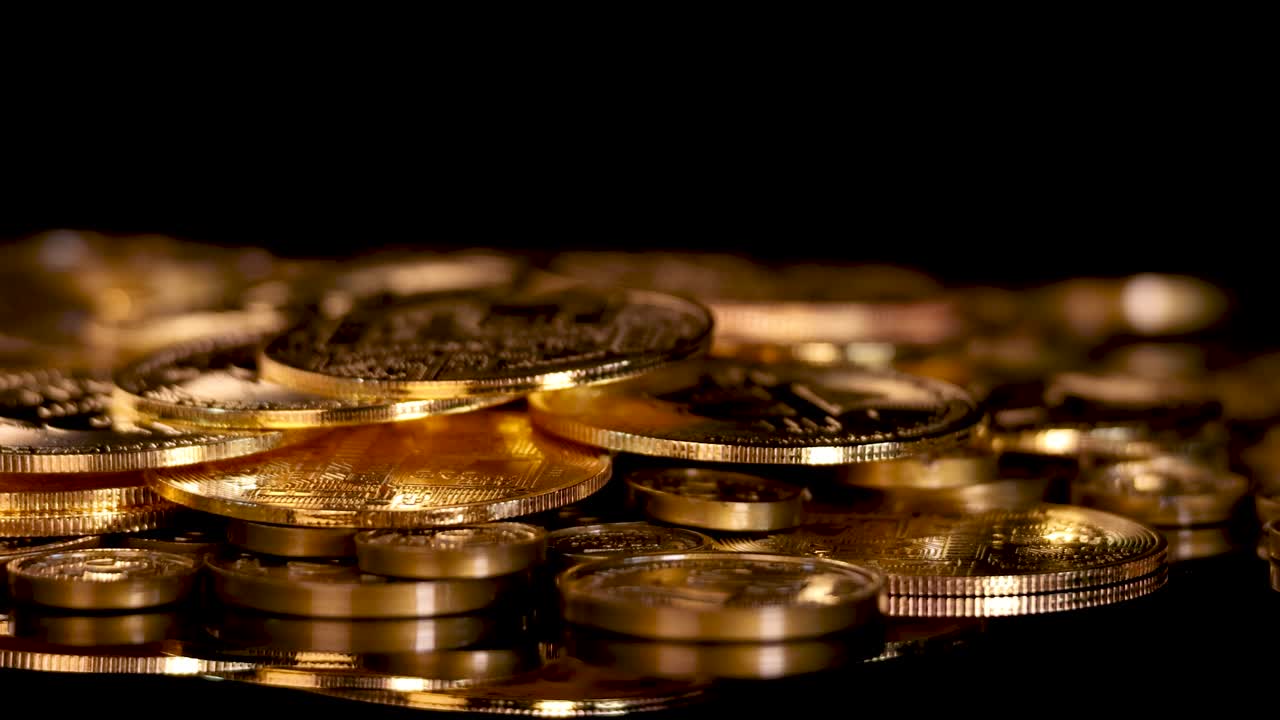 Low-angle rotating shot of golden digital currency coins, dramatic lighting, black background, shallow focus