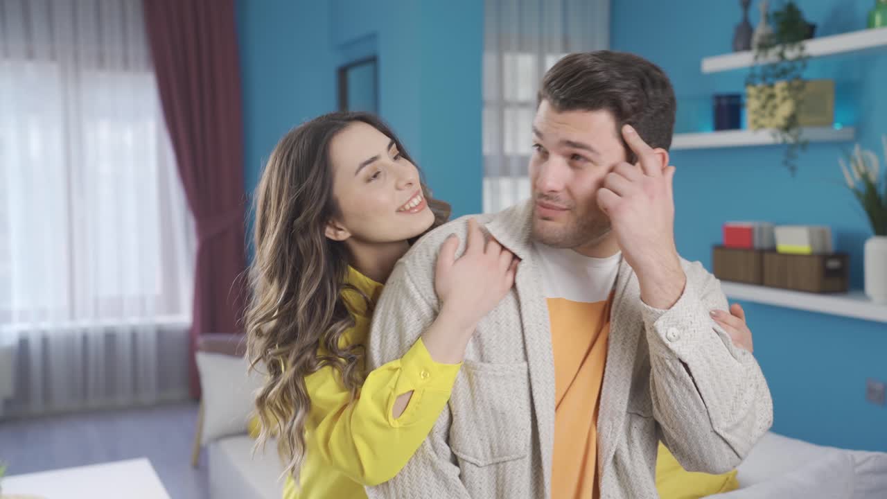 생각 많은 남자가 집에서 아이디어에 대해 생각하고, 그의 아내는 그를 뒤에서 포옹하고 그들은 행복합니다.