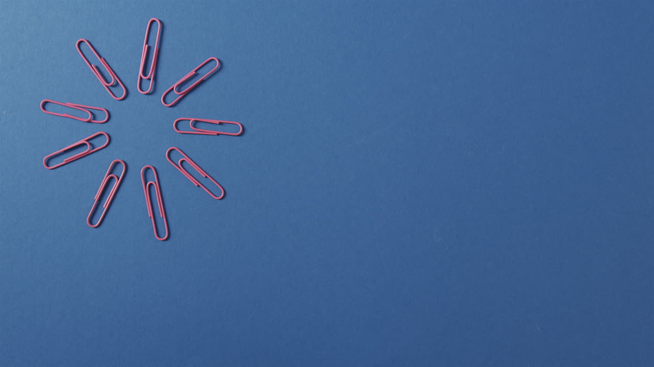 Red paper clips are arranged in a circular pattern on a blue background, with copy space