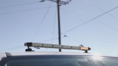 barra de luces con un patrón horizontal amarillo y blanco en un camión de trabajo con una estructura de servicios eléctricos difuminada en el fondo