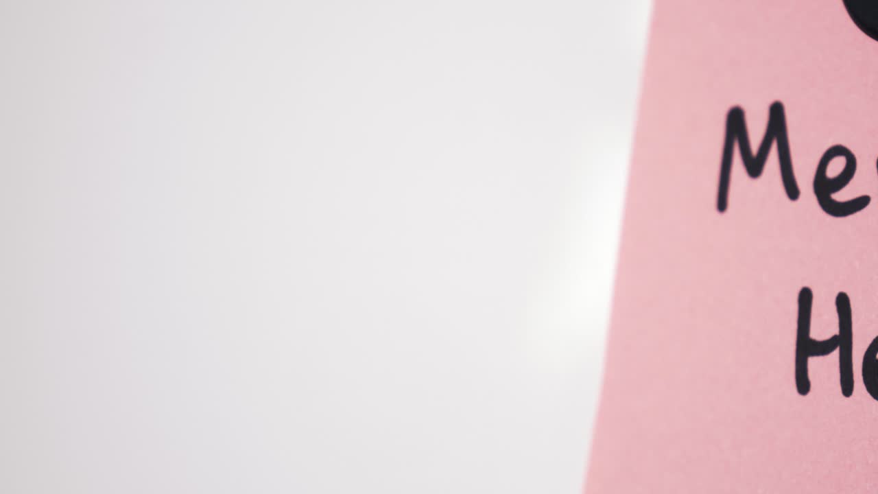 Pan reveal of Mental Health text on pink note held by magnet on whiteboard with selective focus