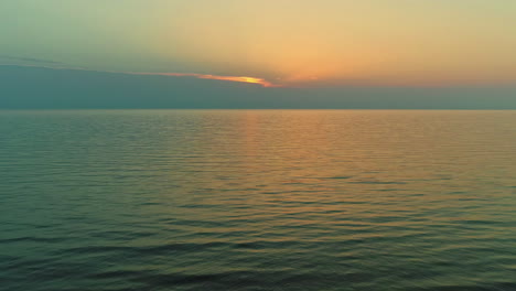 Vista-Aérea-De-Drones-Volando-Sobre-El-Mar-Hacia-La-Puesta-De-Sol-En-El-Horizonte