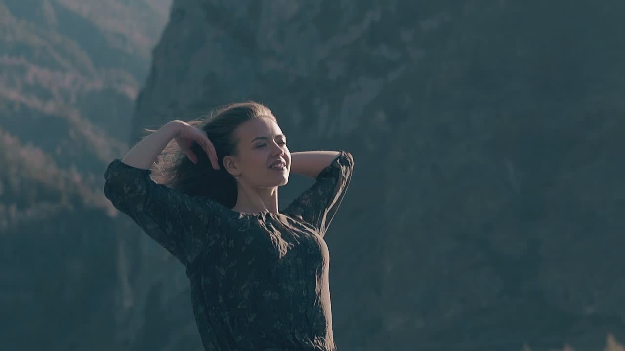 счастливая женщина в платье поднимает руки в ветреный день в замедленном движении