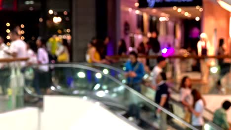 blurred people going down the escalator in the shopping mall