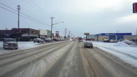 pov shot driving in dawson city, passing snowy streets and buildings, winter day, in yukon, canada