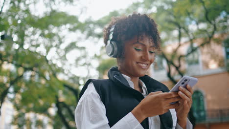 Señora-Alegre-Escuchando-Música-Con-Auriculares-Sosteniendo-El-Teléfono-De-Cerca-Vertical