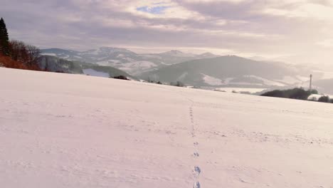 Aerial-low-angle-towards-traces-on-white-Snow,-Mountains-as-background---Slovakia