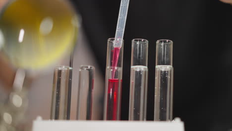 taking pink liquid from tube with pipette in chemical lab