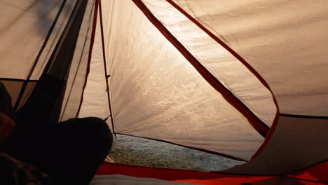 shot from inside a camping tent showing a hiker unzipping and re-zipping the tent flap to check the sunrise view outside.