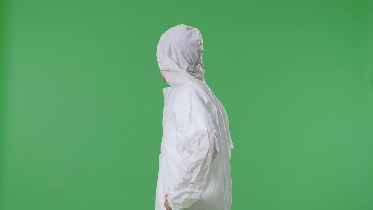 아시아 남성 과학자가 이에 손을 고 녹색 화면 배경에서 주위를 둘러보고 있는 측면 시각