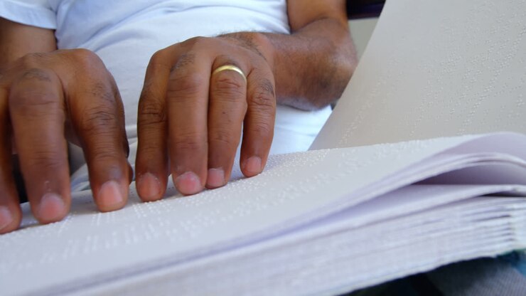 Close-up of blind senior man reading braille book in a comfortable home 4k