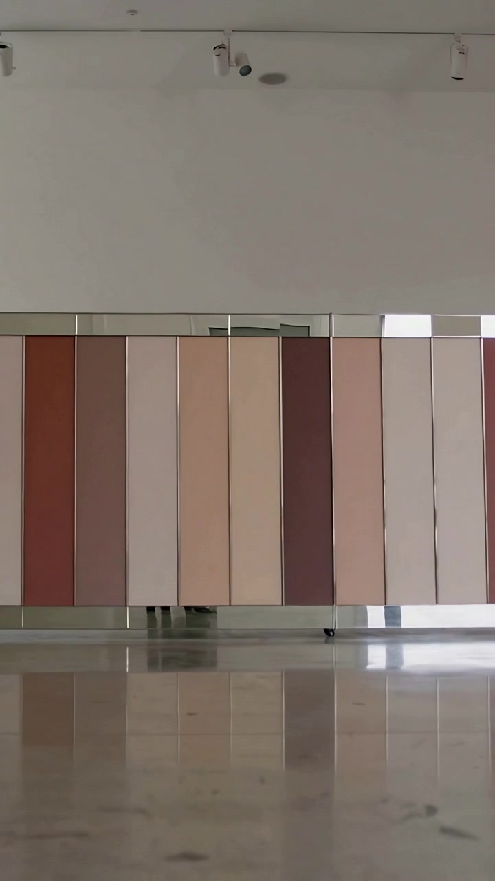 Vertical video: Moving gallery partition showing dark shoes sliding under panels in exhibit, book