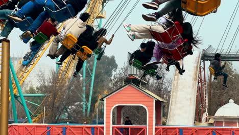 spinning chairs passing by full of people establishing in the amusement park in fantasilandia, tsunami attraction in the background. family atmosphere