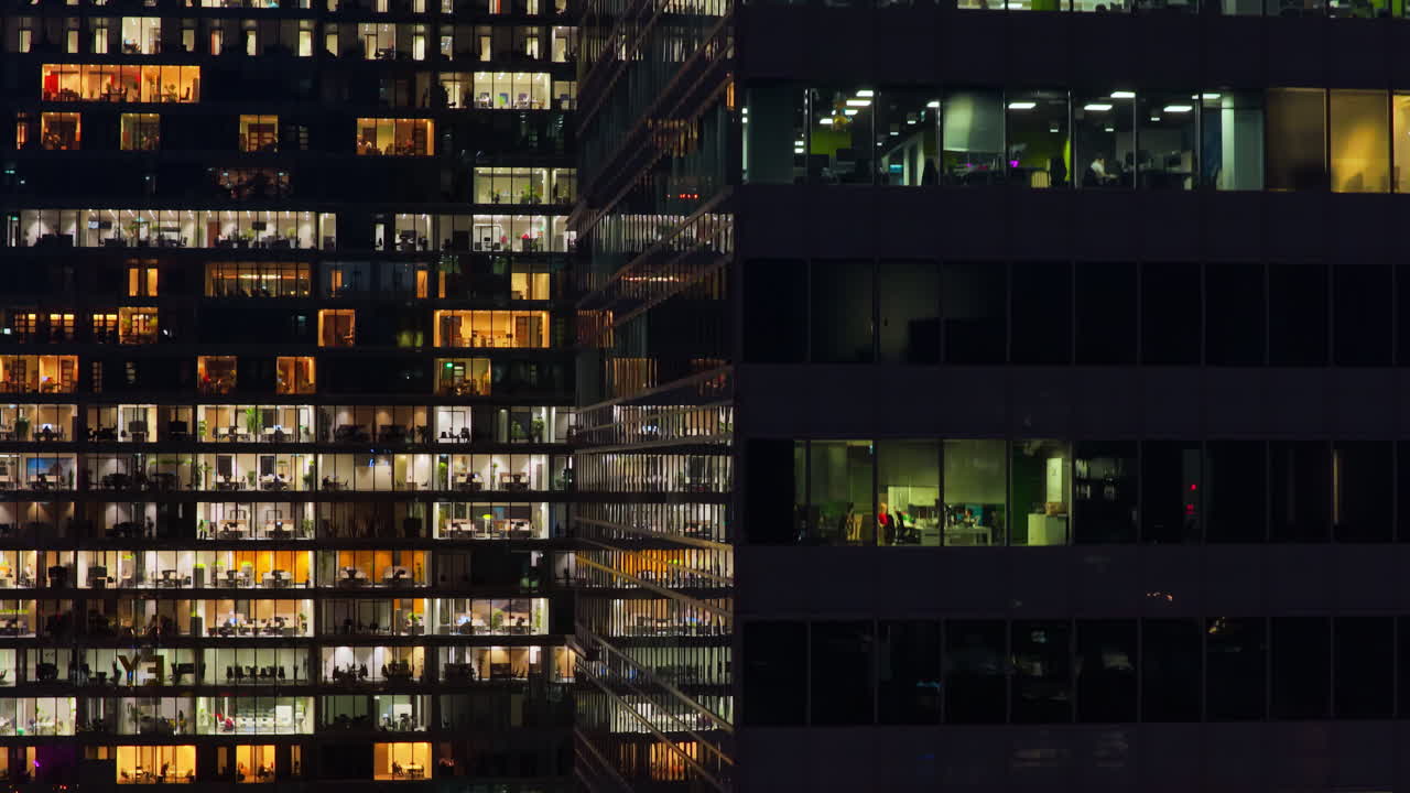 Aerial drone view of illuminated office windows inside a modern skyscraper in central Warsaw