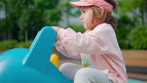 korean-ukrainian girl rocking on riding toy while playing in playground