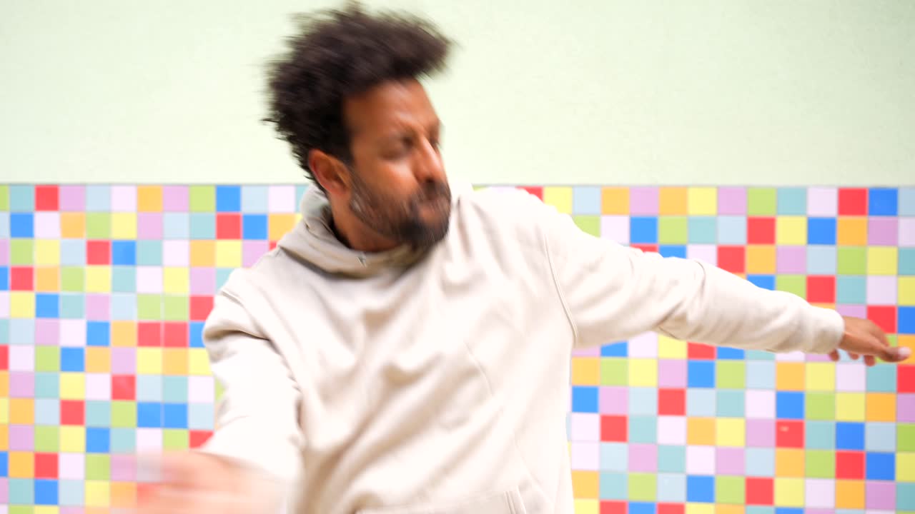 Man dancing in front of colorful tiled wall