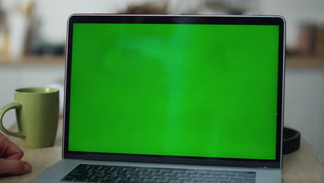 closeup greenscreen laptop computer on office table. unknown man working chroma