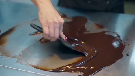 confectioner prepares chocolate glaze using cooking scraper