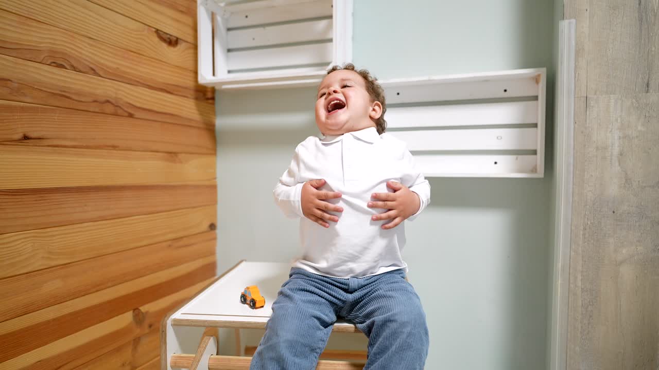 Joyful Toddler Boy Laughing While Sitting in a Room