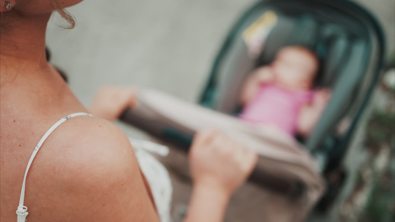 Woman in floral dress pushing a baby stroller outdoors