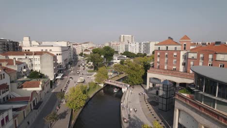 tiro aéreo de arrancada capturando pessoas passeando e barcos moliceiro navegando no canal de água