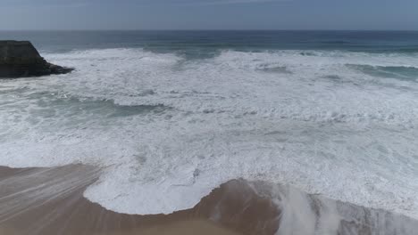 Aerial-shot-of-a-turquoise-ocean-boiling-with-foamy-storm-waves