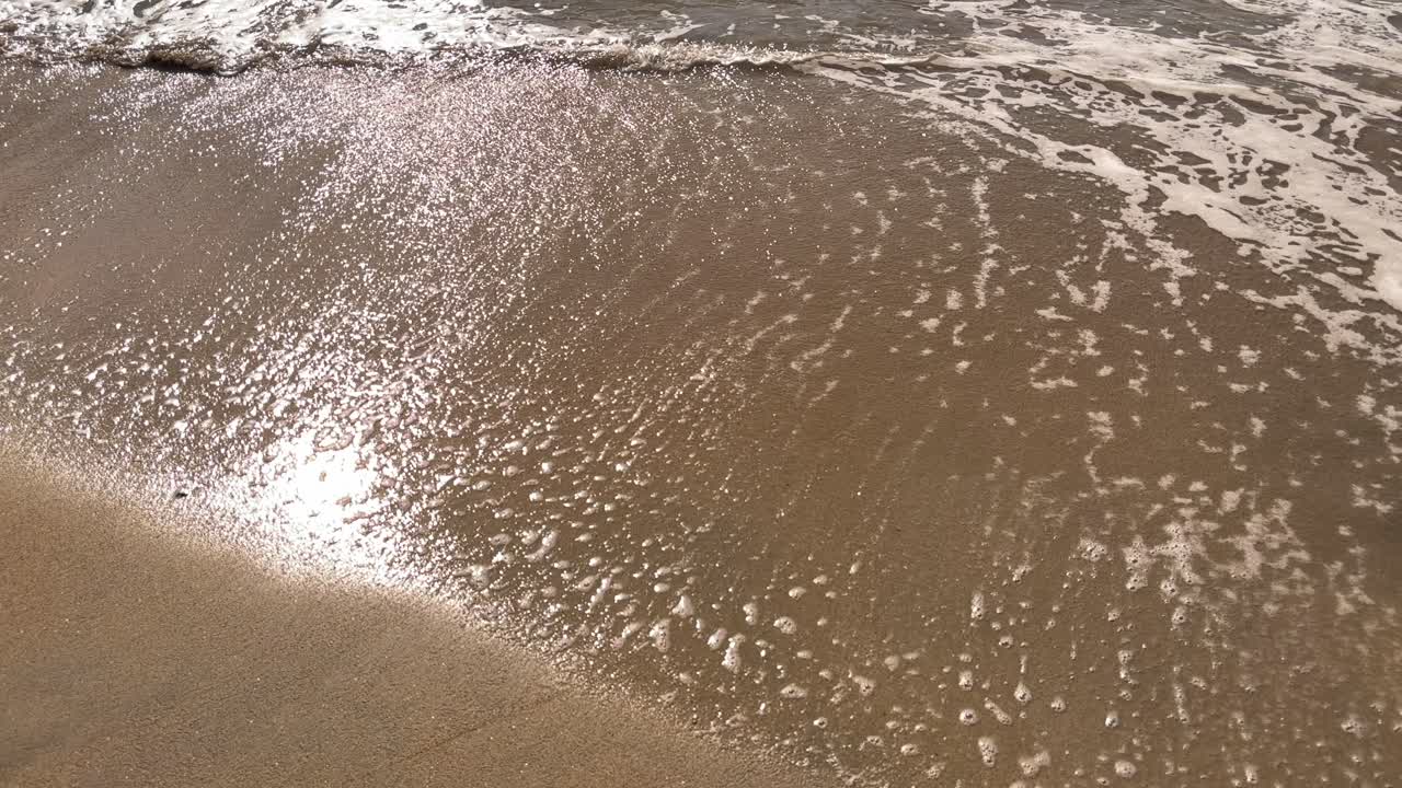 스페인 마요르카의 황금빛 모래 해변에 부드러운 바다 거품과 햇빛이 반사되는 모습