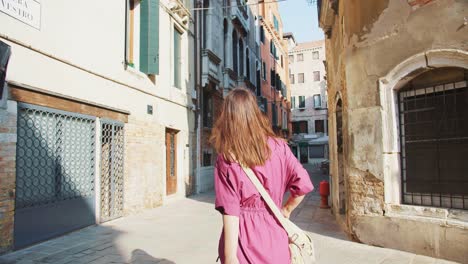 camera follows young female tourist exploring amazing ancient narrow streets during holiday vacation in venice, italy.