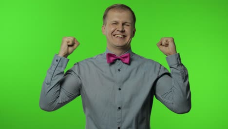 happy man raising fist in victorious gesture, dancing, celebrating great success, enjoying lucky day