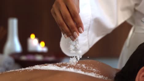 beauty therapist pouring salt scrub on back