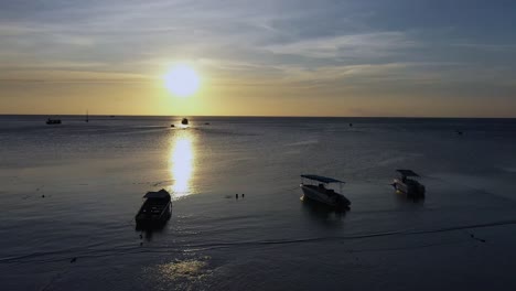 Toma-Aérea-De-Drones-Con-Cámara-Moviéndose-Desde-La-Playa-Sobre-El-Océano-Tranquilo-Hacia-El-Sol-En-Koh-Tao,-Tailandia